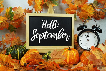 Sticker - Hello September text on chalkboard with alarm clock and maple leaf decoration on wooden background