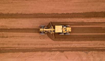 Aerial view road motor grader flatting dirt road surface, Motor grader road construction grader industrial machine on construction site of new road.