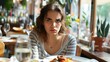 © Dentma Art - A woman with a stern look sits at a table with her meal