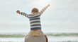 © Maass/peopleimages.com - Father, child and shoulders with back by ocean for airplane, connection or cheers with bonding at beach. Dad, kid and flight with games, love or plane for family on vacation with celebration by waves