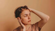© Mehran - A concerned woman is shown on a beige backdrop experiencing hair loss. This image serves as a call to attention for hair loss awareness month.