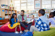 © Rido - Teacher reading book to his little students in a library