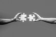 © Yevhen - Men holding and putting a piece of jigsaw puzzle together. Two hands trying to connect couple puzzle piece. Black and white