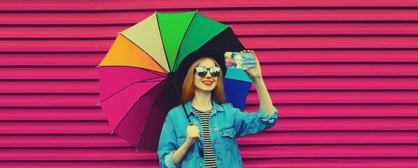 Wall Mural - Beautiful happy smiling young woman taking selfie with phone, stylish girl holding colorful umbrella