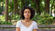 © Arcane Imaginarium - Young woman meditating sitting on a park bench practising mindfulness mental health concept