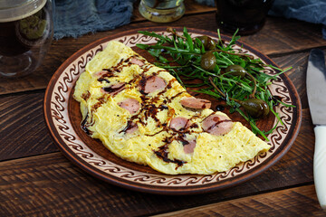 Wall Mural - Fried omelet stuffed with sausage. Omelette with arugula and capers