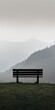 © nitnicha - Lonely bench overlooking foggy mountains, perfect for themes of solitude, peace, and nature's beauty in stock photography.