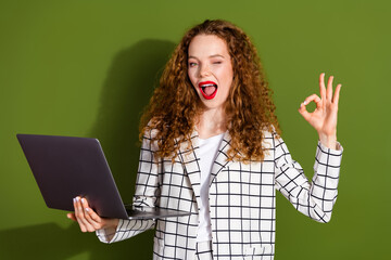 Wall Mural - Photo portrait of pretty young girl netbook wink show okey wear trendy white plaid outfit isolated on khaki color background