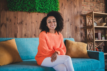 Wall Mural - Photo of adorable sweet lady wear orange sweater smiling enjoying weekend sitting sofa indoors room home house