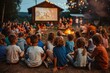 © Milos - A large group of friends and family gather outside at night, sitting around a campfire and watching a movie projected on an outdoor screen at a campsite.