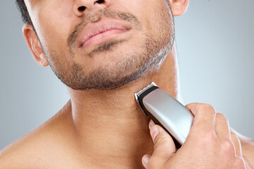 Canvas Print - Shave, electric razor and man cutting beard hair for grooming and hygiene or health on a gray studio background. Morning, routine and equipment with model with trimmer for haircare and wellness