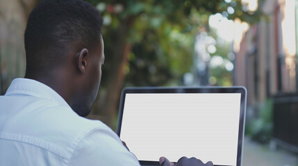 Wall Mural - laptop mockup over shoulder shot of a young man using laptop with blank white screen for mockup