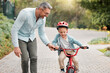 © peopleimages.com - Father, son and learning to ride bicycle in outdoor, parent support and training activity for kid. Dad, boy and teaching cycling outside or helping for child development, happy and helmet for safety
