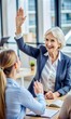 © Tekin - Aged female business trainer or coach giving high five to trainee for correct answer, old lady team leader joining hands with happy young woman worker acknowledging her good idea or perfect result