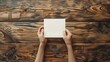 © Studios - A woman hand places a note on the clean wood table bird view