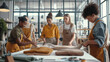 © Natalia - Group of women collaborating in a workshop, engaged in working with fabric, wearing aprons, modern industrial-style interior with large windows and tools around.