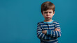 © Natali - Mad male kid, angry little boy standing with his arms crossed, and looking at the camera with upset face expression. Unhappy toddler, studio shot, annoyed and frustrated child emotion