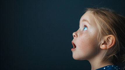 Wall Mural - A young girl with blue eyes is looking up at something