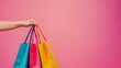 © Joyce - Hand holding shopping bags over plain background