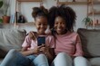© Coconut Design - African girl and young mother sit on sofa with smartphone, enjoy video conference talk event with family, smiling watching funny online content, amusing videos. Modern technology, fun, Generative AI