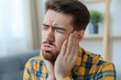 © Igor - Man with toothache holds her cheek with painful expression on face