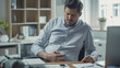 © CosmoJulia - Man holding his stomach in discomfort while sitting in office
