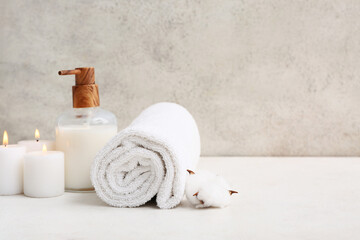 Canvas Print - Clean soft towel, bottle of cosmetic product and candles near grunge wall in bathroom, closeup