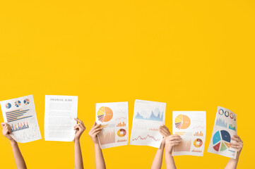 Wall Mural - Female hands with financial graphics and documents on yellow background