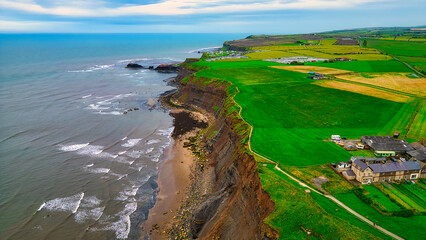 Wall Mural - Aerial view of coastal cliff with green fields and ocean in Whitby, North Yorkshire