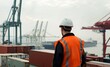 © Oksana - Worker in high-visibility vest and helmet overlooking shipping containers and cranes at a port. Industrial logistics and transportation concept.