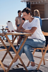 Canvas Print - Smile, phone call and woman with laptop, outdoor and restaurant in morning for scriptwriter with sunglasses. Summer, listening and happy with computer and paper for inspiration, web and creative