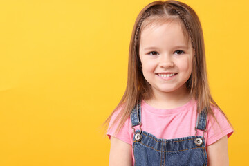 Wall Mural - Portrait of happy little girl on orange background, space for text