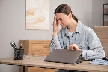 Canvas Print - Embarrassed woman at wooden table with laptop in office