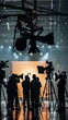 © Maria Mikhaylichenko - Behind-the-scenes view of a bustling TV studio set, with silhouettes of camera operators and crew against bright lights and equipment rigging overhead.