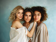 © Carmen - Diverse group of women friends against a blue background, beautiful skin and hair, copy space