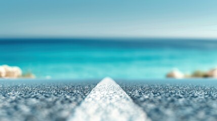 Canvas Print - A road with a white line and a blue ocean in the background