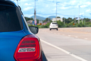 Wall Mural - Rear side of car blue color parking beside of concrete road. Background of concrete path curves and traffic passes by.