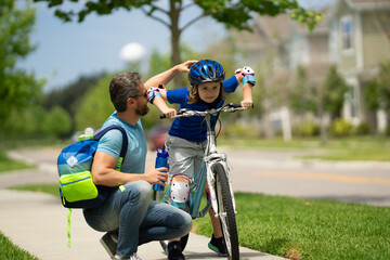 Poster - Father and son riding bike in park. Child in safety helmet with father riding bike in summer day. Father teaching son riding bike. Fatherhood. Support parent. Fathers day. Child care. Fathers day.