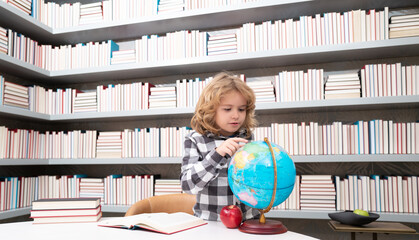 Fototapete - School and students in classroom. Education kids. Clever Child pupil student in the school class. Studying and learning concept. School boy in library near school supplies. Kid learn geography with