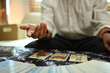 © Prathankarnpap - Fortune teller reading tarot cards on table with a mystical cloth. Forecasting and divination concept