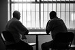© tynza - A prison inmate meeting with their defense attorney in a visiting room, discussing legal strategy and next steps.