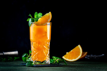 Wall Mural - Summer alcoholic cocktail drink with vodka, rum, orange juice,  crushed ice and mint. Black background