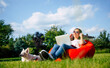 © My Ocean studio - Beautiful happy young woman freelancer works with laptop sitting on bean chair bag on backyard lawn with her own lovely white dog. Rest and relax. Business person, shopping, online, play game