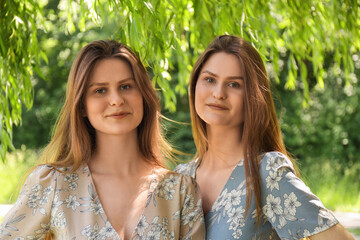 Canvas Print - Portrait of two beautiful twin sisters in park