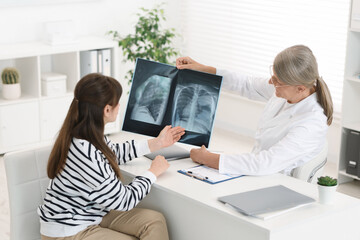 Poster - Lung disease. Doctor showing chest x-ray to her patient at table in clinic