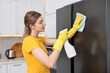 © New Africa - Professional janitor wearing uniform cleaning fridge in kitchen