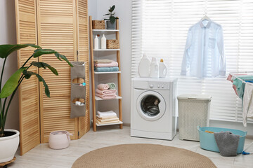 Poster - Washing machine, detergents, towels, baskets and folding screen in laundry room