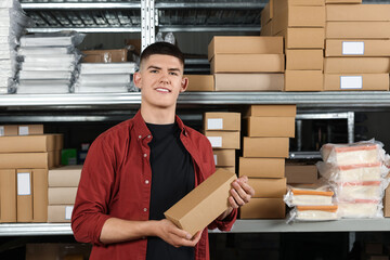 Poster - Smiling young man with cardboard boxes in auto store