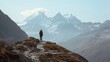 Hiker takes in the scenic mountain vista from a ridge, with a valley and snow-capped peaks in the distance