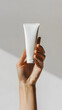 © Oksana - Closeup woman's hand holding a white tube of skin cream isolated on white background